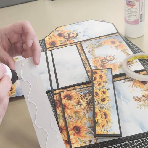 Craft adhesives used for scrapbooking and cardmaking projects with sunflower-themed paper designs.
