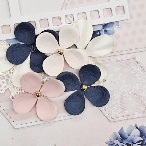 Cluster of navy, blush, and ivory paper flowers with gold centres on a pastel scrapbook background — thumbnail for the Flower craft-embellishments category.
