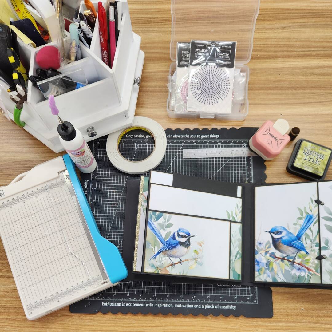 Papercraft supplies and scrapbooking tools with handmade bird-themed card project.